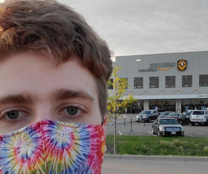 Amazon worker appearing in front of warehouse speaking about employer retaliation.